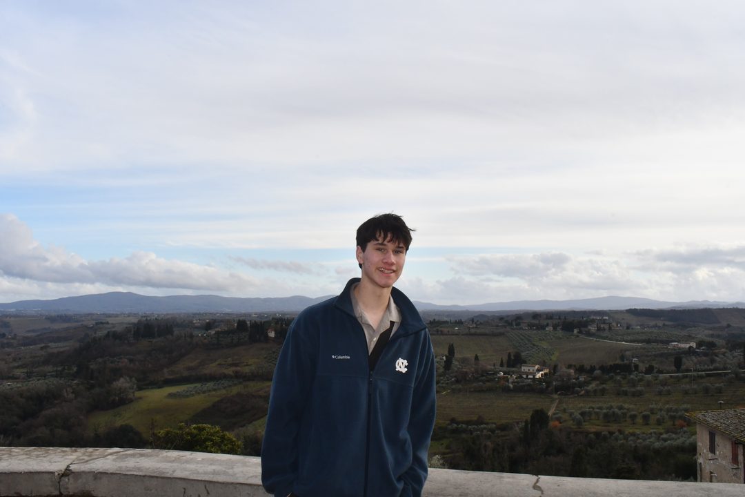 Ayden standing at a stone wall above rolling green hills.